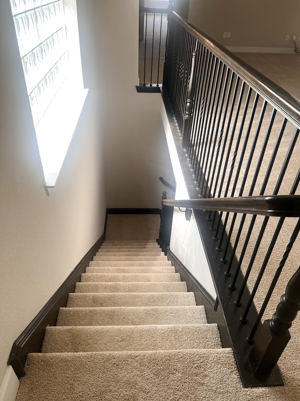 Brand-new carpet on the staircase with wrought-iron railing