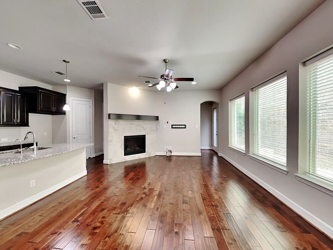 Open living room with a stone fireplace and rich hardwood floors