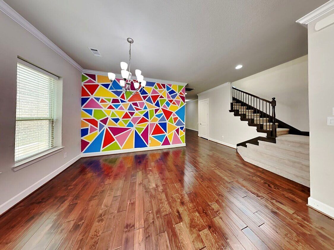 Dining area with colorful geometric accent wall and staircase