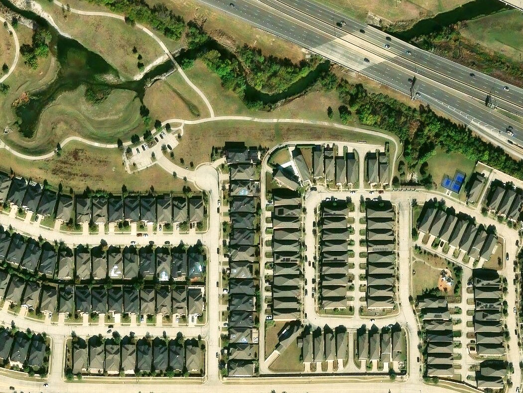 Aerial view of the Parkside neighborhood with Parkside Commons green space, pond, and walking trails behind the home